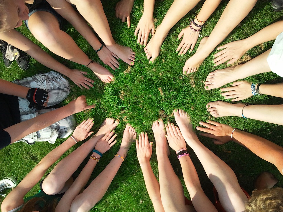 hands all together in a circle on grass